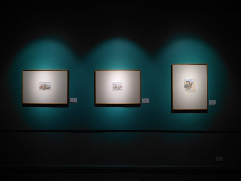 Framed artworks illuminated on a museum wall in Manila, capturing modern aesthetics.